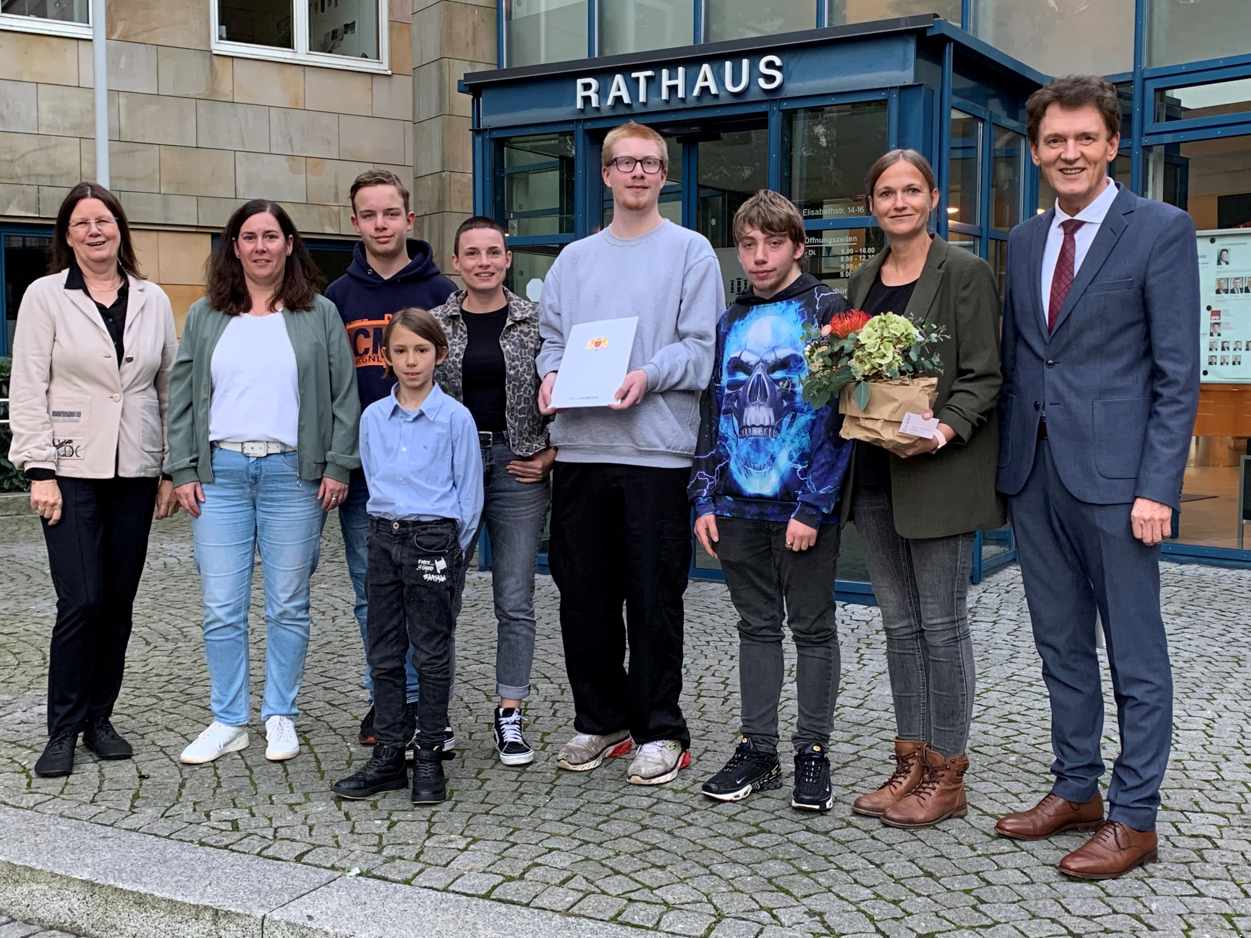 Eine Gruppe von neun Personen steht vor dem Haupteingang des neuen Rathauses.