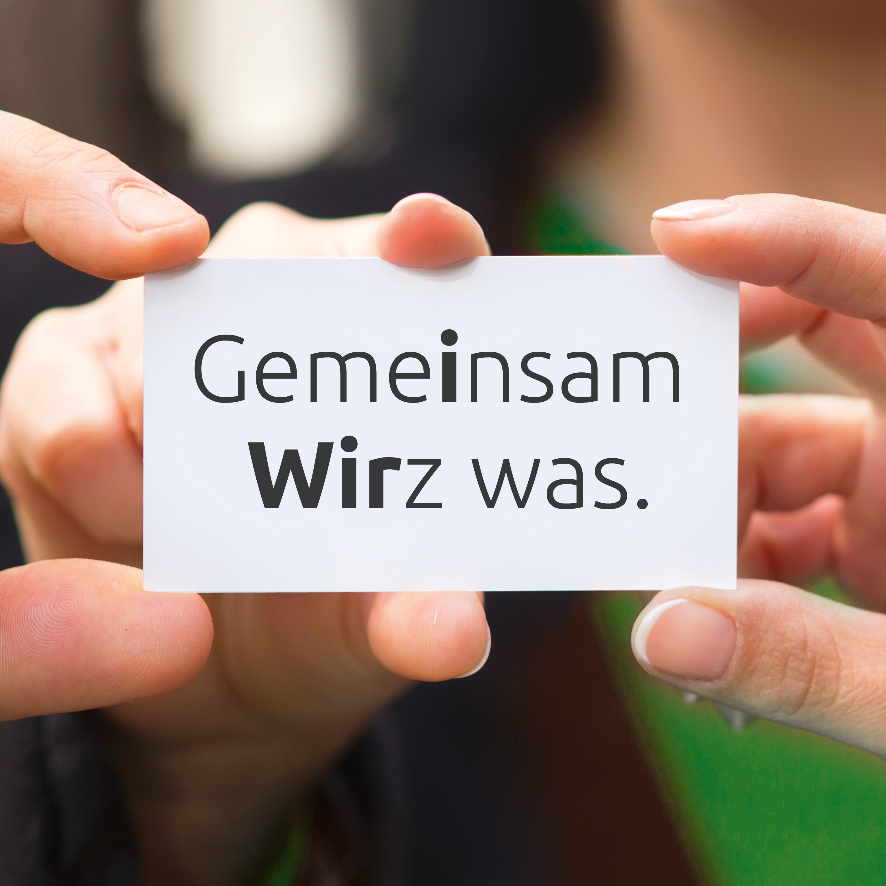 Mehrere Hände halten ein weißes Schild mit schwarzer Schrift in den Händen. Auf dem Schild steht: Gemeinsam Wirz was