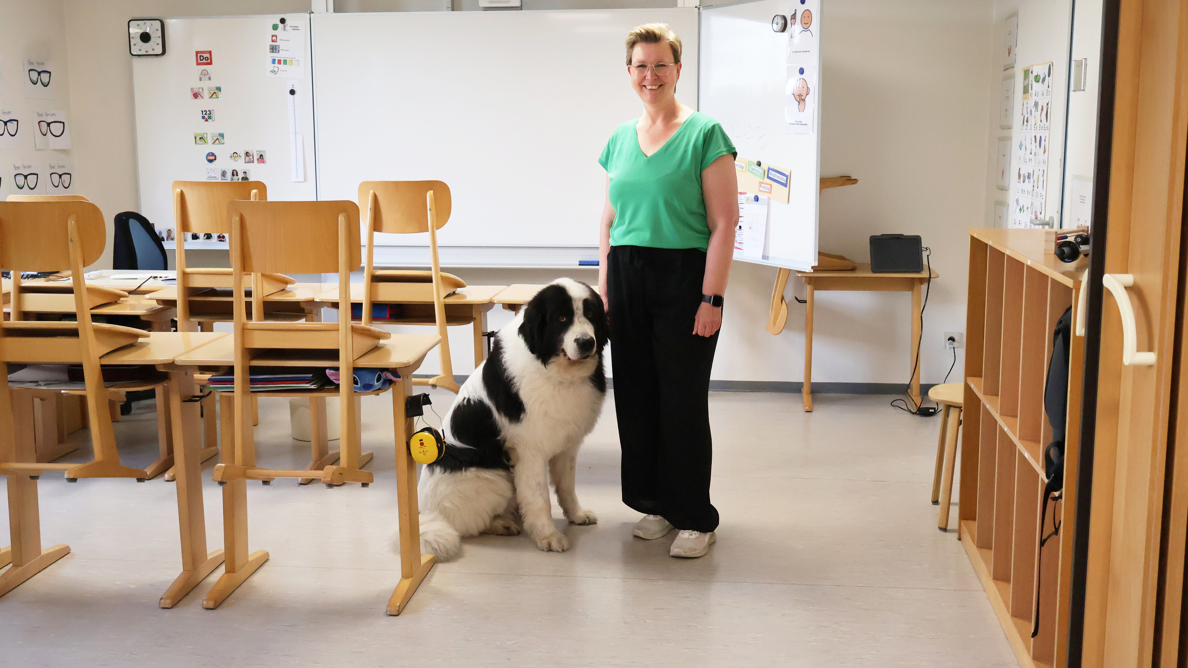 Anita Mell, Sozialp&auml;dagogin in der Mosaik-Schule, steht mit Hund Bruno vor der Tafel im Klassenzimmer.