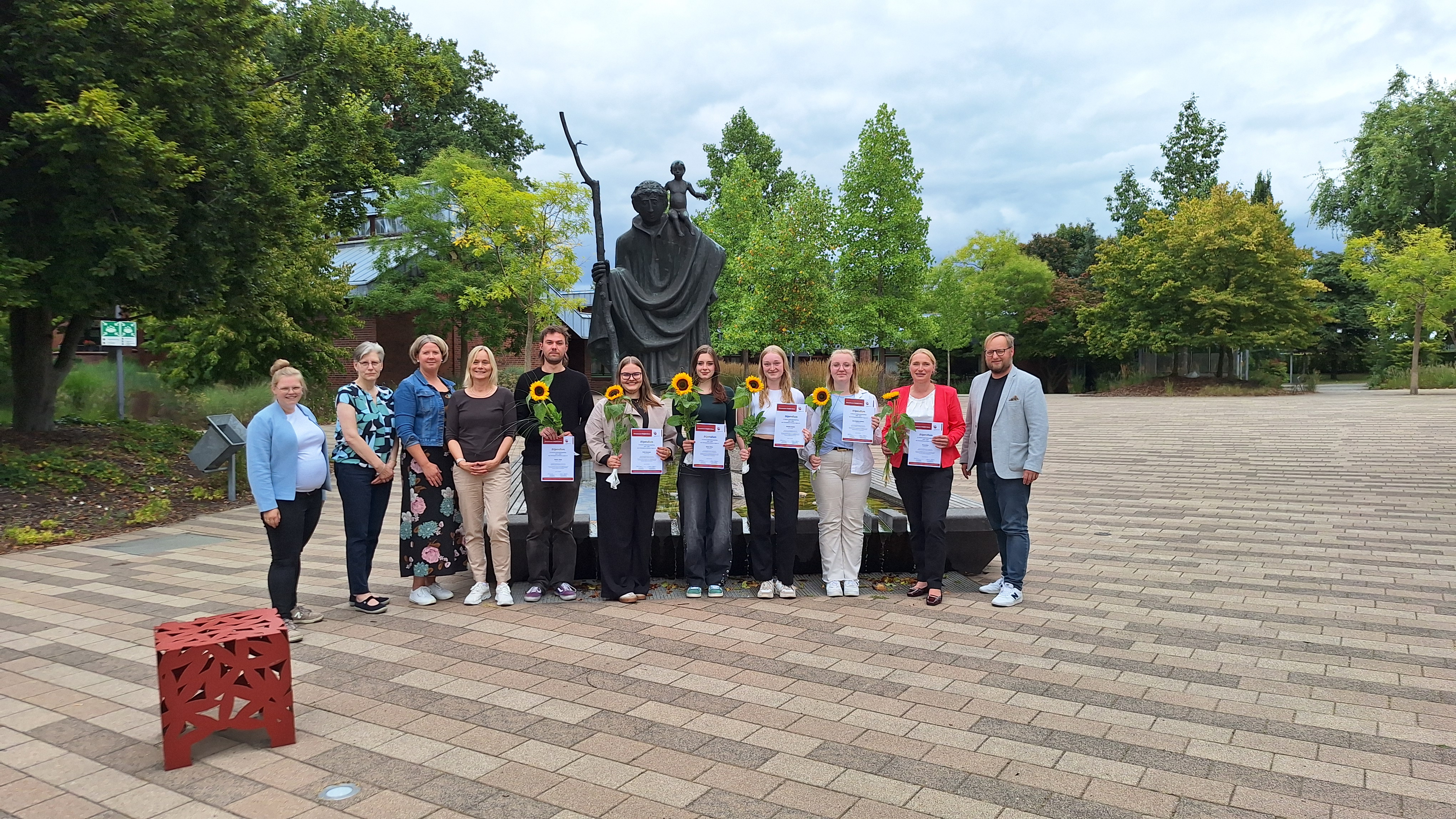 Eine Gruppe von Menschen steht vor Christophorus Statue