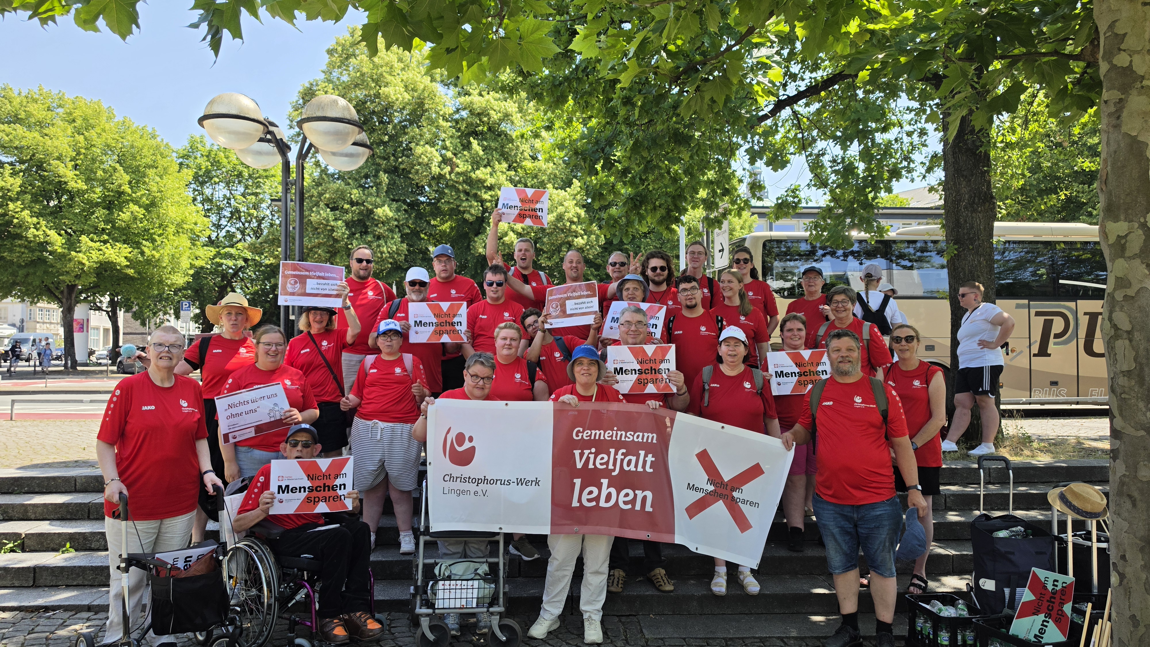 Eine Gruppe Menschen in roten Tshirts. Sie halten Schilder in den H&auml;nden.
