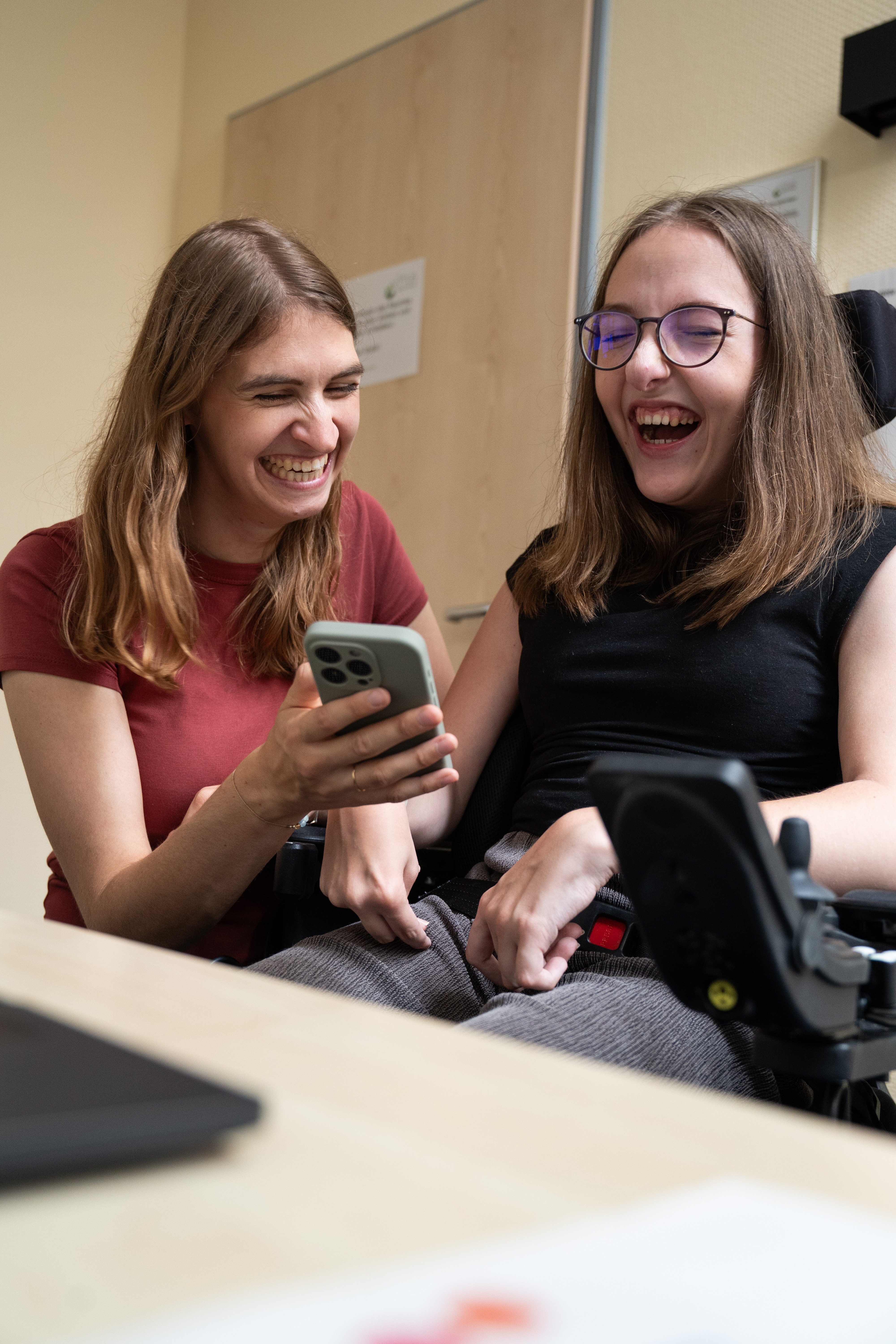 Zwei Frauen lachen w&auml;hrend sie sich etwas auf dem Smartphone angucken.