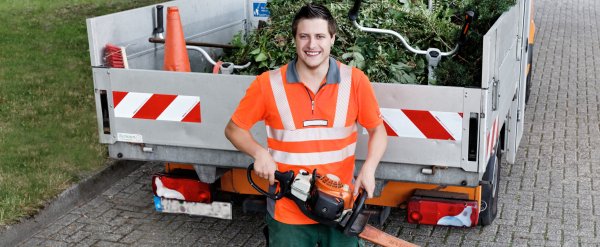 Teilnehmer steht mit elektrischer Heckenschere vor einer Ladefläche mit Grünabfall.