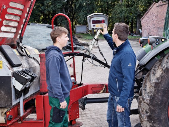 Anleiter erklärt einem Auszubildenden den Bildschirm am Futtermischwagen.