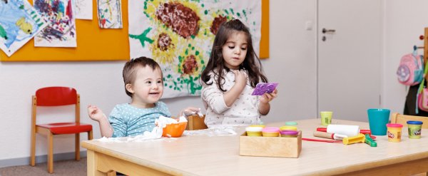 Zwei Kinder spielen an einem Tisch mit Rasierschaum und Knete.