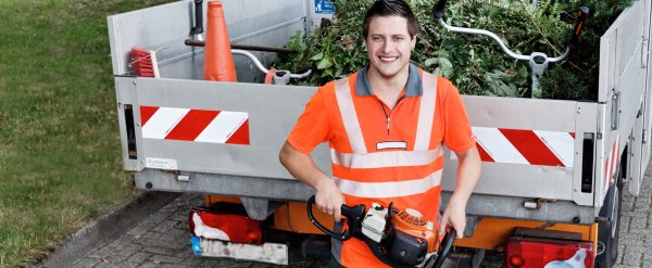 Teilnehmer steht mit elektrischer Heckenschere vor einer Ladefläche mit Grünabfall.
