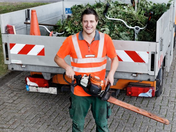 Teilnehmer steht mit elektrischer Heckenschere vor einer Ladefläche mit Grünabfall.