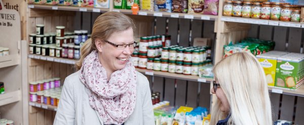 Kauffrau im Einzelhandel und Beschäftigter im Laden hinter Gemüsekisten.