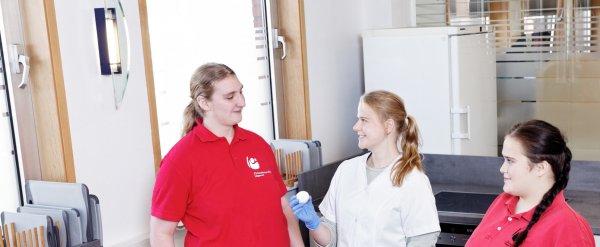 Anleiterin zeigt zwei Auszubildenden die Zutaten für das Backen.