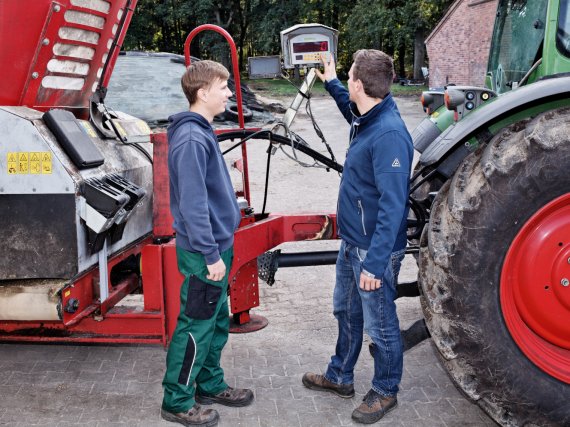 Anleiter erklärt einem Auszubildenden den Bildschirm am Futtermischwagen.