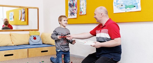Mitarbeiter und Kind spielen mit Lego-Bauklötzen.