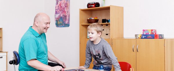 Mitarbeiter und Kind spielen Gesellschaftsspiel.