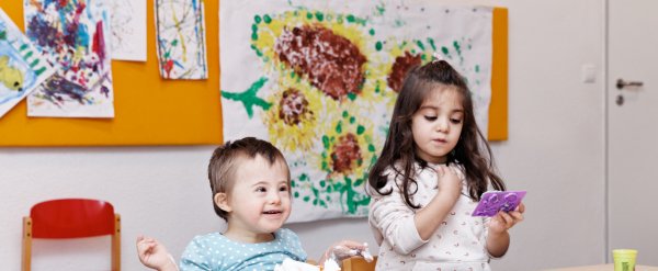 Zwei Kinder spielen an einem Tisch mit Rasierschaum und Knete.