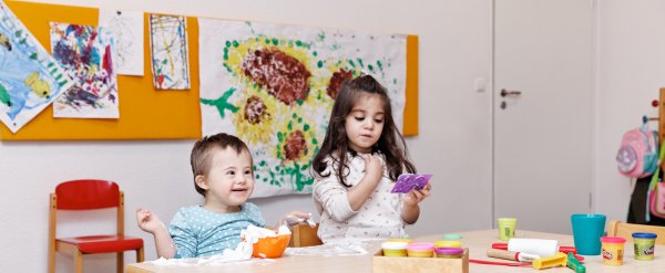 Zwei Kinder spielen an einem Tisch mit Rasierschaum und Knete.