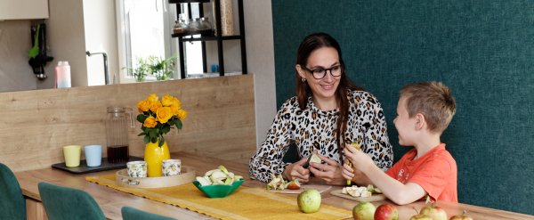 Mutter und Kind schneiden Äpfel in der Küche.