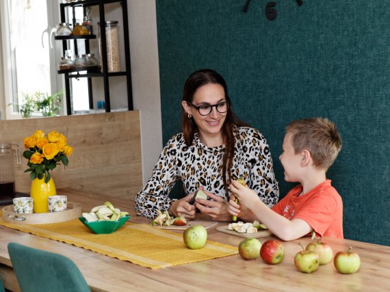 Mutter und Kind schneiden Äpfel in der Küche.