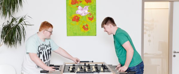 Zwei Jugendliche spielen Tischkicker.