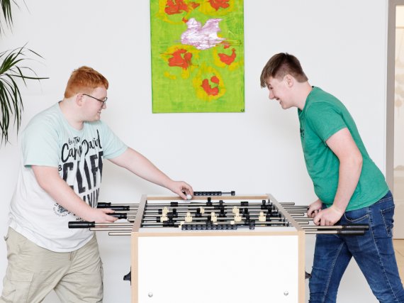 Zwei Jugendliche spielen Tischkicker.