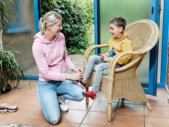 Mitarbeiterin hilft Kind beim Schuhebinden.