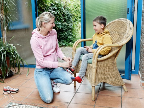 Mitarbeiterin hilft Kind beim Schuhebinden.