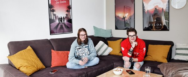 Zwei Jugendliche schauen auf dem Sofa gemeinsam Fernsehen.