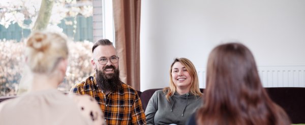 Erzieherin und Erzieher auf Sofa im Gespräch mit zwei Klientinnen.