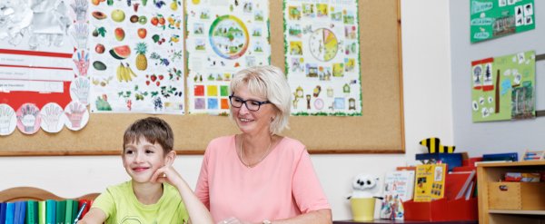 Schulbegleiterin hilft Kind bei einer Schulaufgabe.