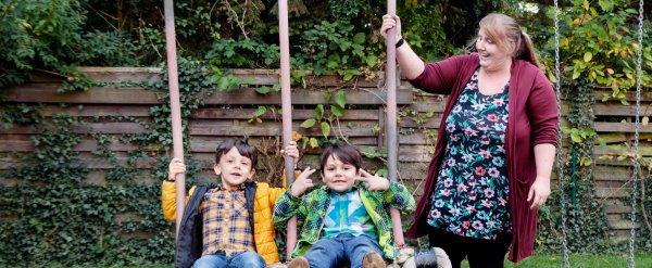 Mitarbeiterin gibt zwei Kindern auf der Schaukel Anschwung.