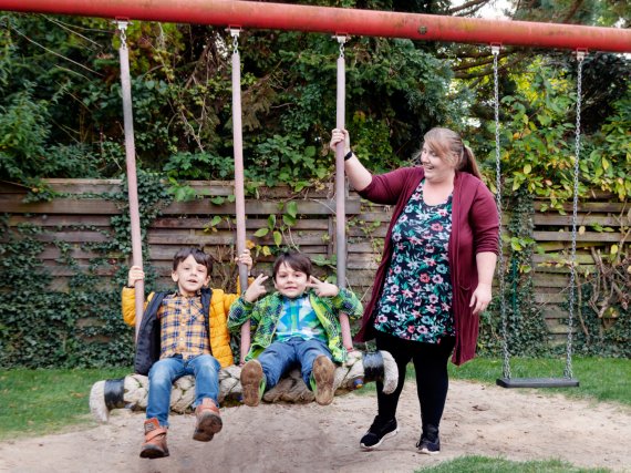 Mitarbeiterin gibt zwei Kindern auf der Schaukel Anschwung.