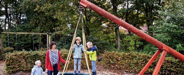 Mitarbeiterin mit drei Kindern an der Nestschaukel.