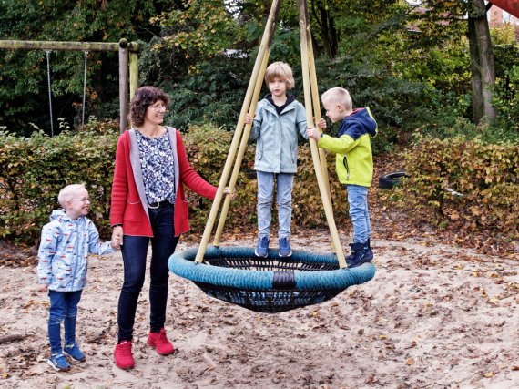 Mitarbeiterin mit drei Kindern an der Nestschaukel..