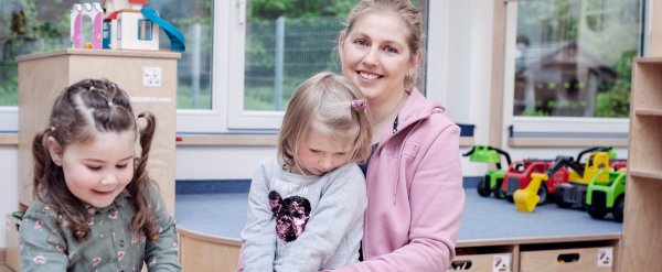 Eine Erzieherin hat ein Kind auf dem Schoß.