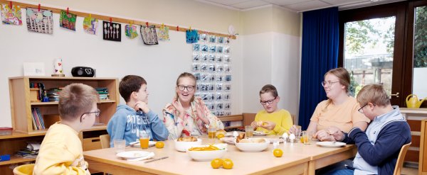 Schülerinnen und Schüler sitzen mit Lehrkräften beim gemeinsamen Frühstück.