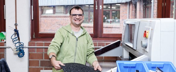 Beschäftigter fertigt Stoffmuster mit einer Maschine.
