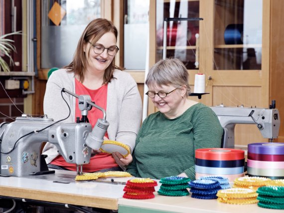 Beschäftigte und Anleiterin an der Nähmaschine in der Schleifenwerkstatt.