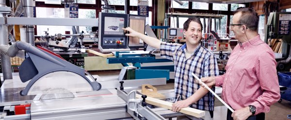 Beschäftigter und Mitarbeiter an Maschine in der Holzwerkstatt.