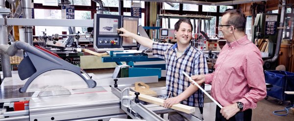 Beschäftigter und Mitarbeiter an Maschine in der Holzwerkstatt.