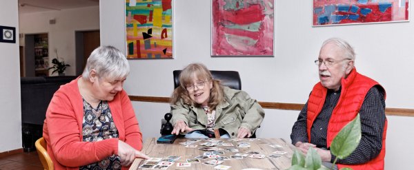 Drei Bewohnerinnen und Bewohner spielen ein Kartenspiel.