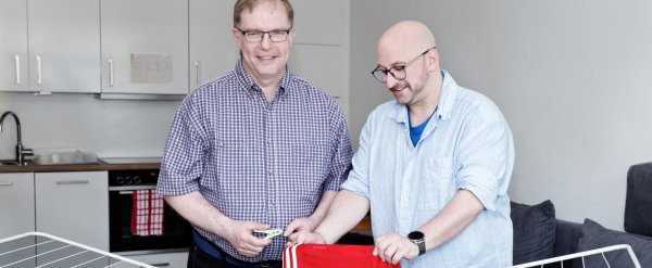 Betreuer hilft Bewohner beim Aufhängen der Wäsche.