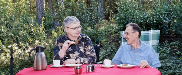 Zwei Bewohner trinken Kaffee und essen Kekse auf der Terrasse.