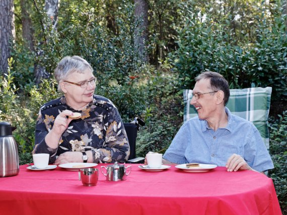 Zwei Bewohner trinken Kaffee und essen Kekse auf der Terrasse.