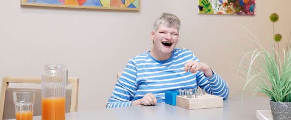 Klientin steckt Schrauben in eine Holzvorrichtung.