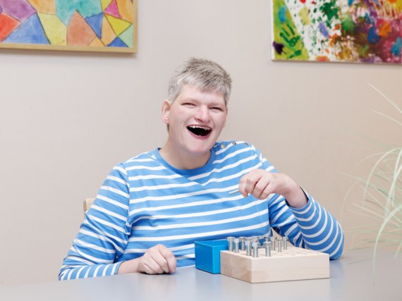 Klientin steckt Schrauben in eine Holzvorrichtung.