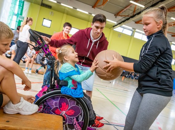 Kinder mit und ohne Behinderung machen gemeinsam Sport in einer Turnhalle
