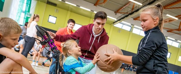 Kinder mit und ohne Behinderung machen gemeinsam Sport in einer Turnhalle.