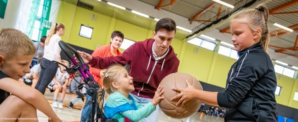 Kinder mit und ohne Behinderung machen gemeinsam Sport in einer Turnhalle