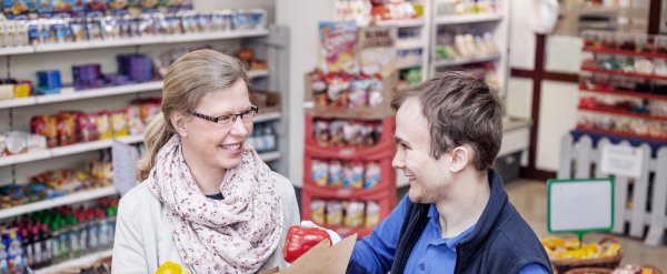 Kauffrau im Einzelhandel und Beschäftigter im Laden hinter Gemüsekisten.